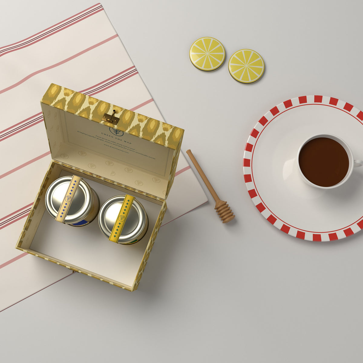 Flat lay of the open 2-jar gift box with tea, lemon slices and a striped napkin.