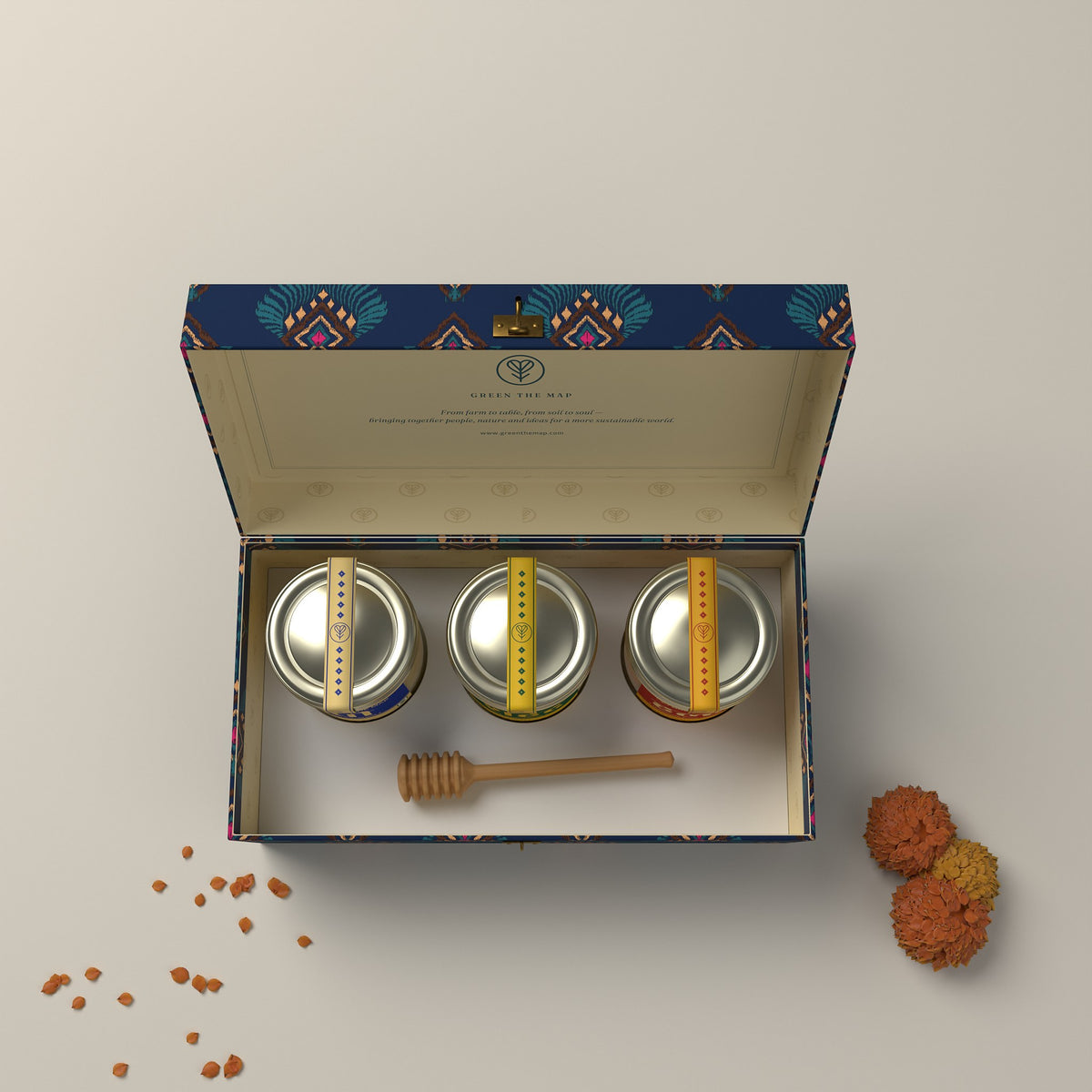Top view of the open 3-jar gift box with gold-capped jars and a wooden honey dipper.