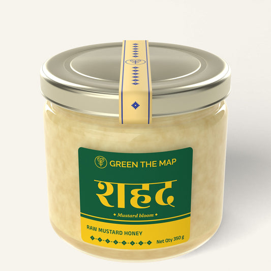 Raw mustard honey 350 g in a glass jar with a green label and a champagne gold cap, on a plain off-white background.