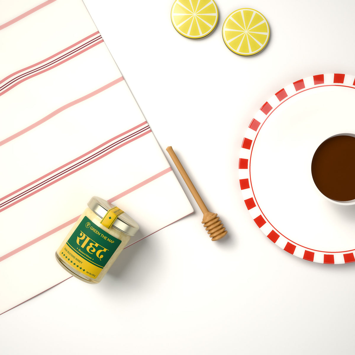 Flat lay of a honey jar with lemon slices, a striped napkin, tea and a wooden dipper.